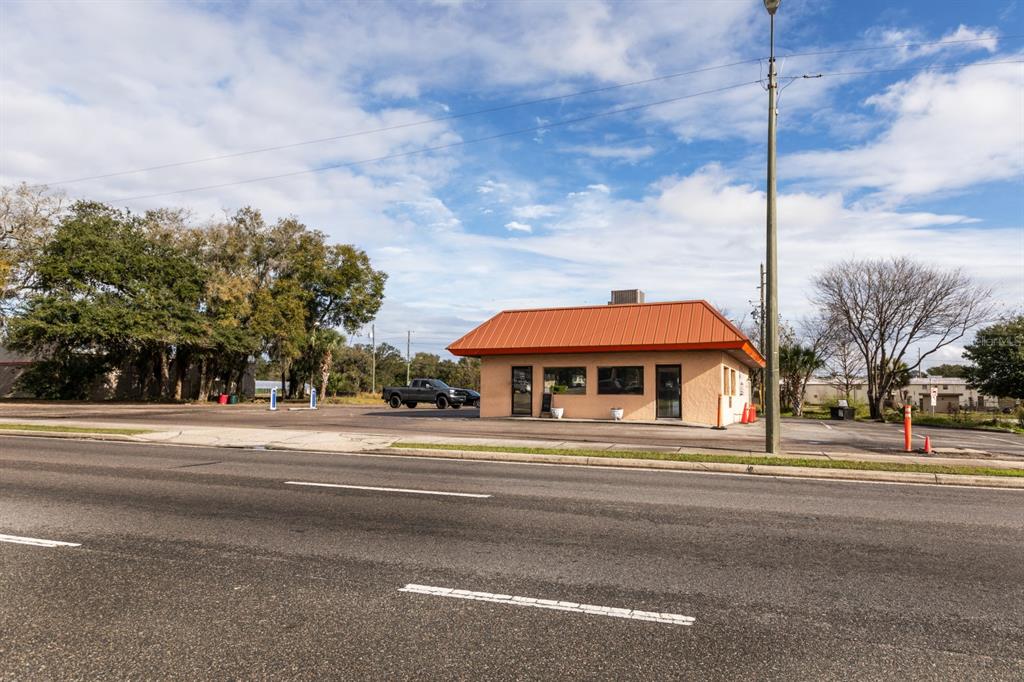 A single-story commercial building with an orange metal roof sits beside a paved road — 299 E BROAD STREET, GROVELAND, FL