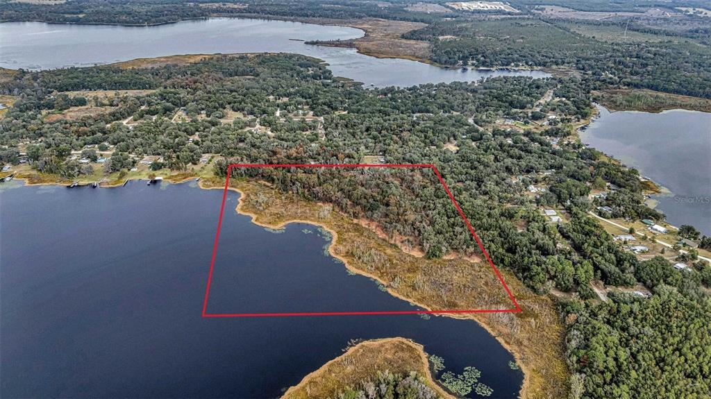 An aerial view shows a wooded plot of land outlined in red bordering a lake — FAYE STREET, HAWTHORNE, FL