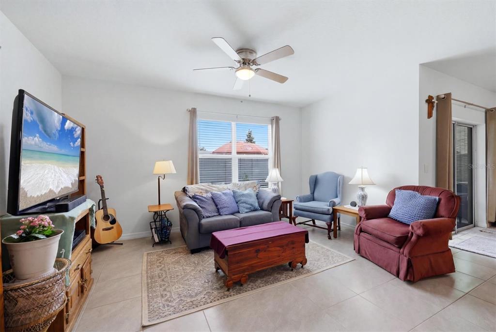 A backyard view shows a screened-in patio, a paved seating area, and a grass lawn — 17917 CANOPY PLACE, BRADENTON, FL