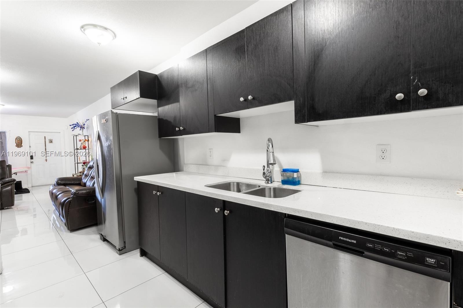 A kitchen features dark wood cabinets, white countertops, stainless steel appliances, and white tile flooring — 1998 NW 47th St, Miami FL 33142, MIAMI, FL