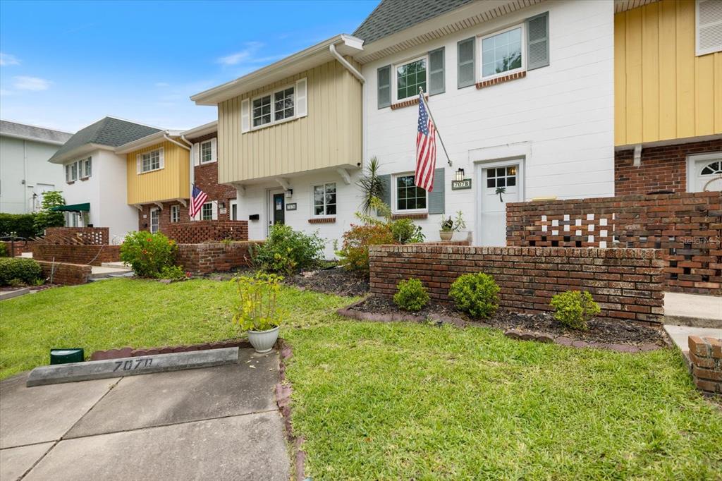 A row of multi-story townhouses features brick lower walls, white and tan siding, and front patios — 707 W VENICE AVENUE UNIT 707B, VENICE, FL