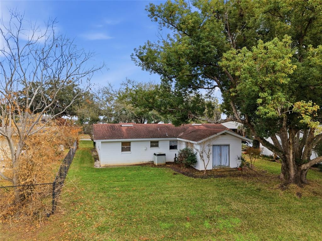 A white, single-story house with a shingled roof sits in a grassy, tree-filled backyard — 530 MAR NAN MAR PLACE, CLERMONT, FL