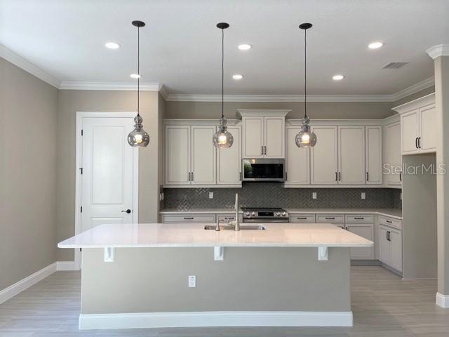 A kitchen features a large white island, light-colored cabinetry, and three hanging pendant lights — 7 OASIS CIRCLE, PALM COAST, FL