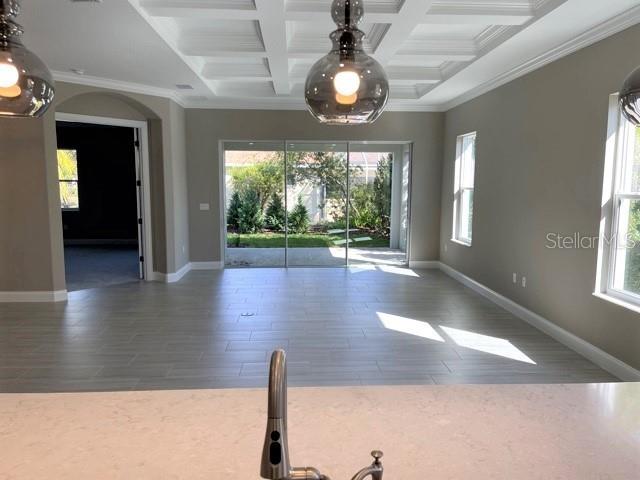 A kitchen island overlooks a living area with a coffered ceiling and sliding glass doors — 7 OASIS CIRCLE, PALM COAST, FL