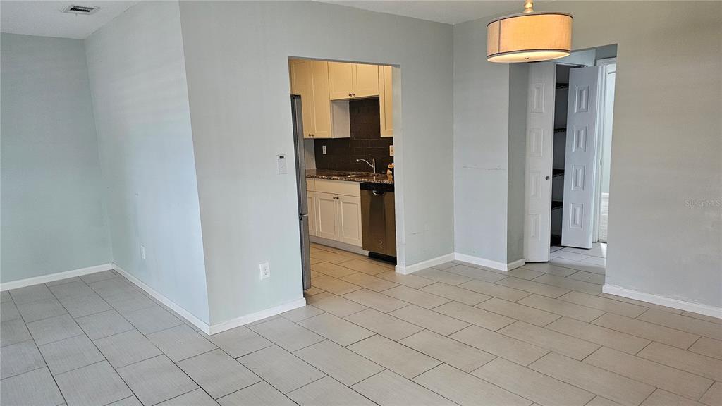 A view of a dining area with tiled floors leading into a kitchen with white cabinets — 1902 DANDRIDGE STREET UNIT 12, SUN CITY CENTER, FL