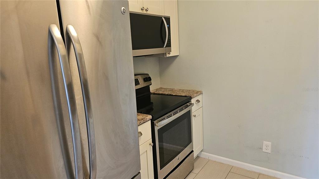 A kitchen features stainless steel appliances, white cabinets, and granite countertops — 1902 DANDRIDGE STREET UNIT 12, SUN CITY CENTER, FL