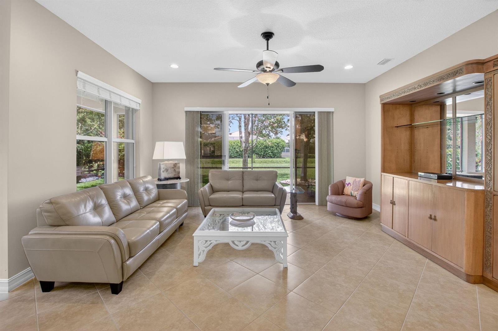 A living room features beige tile floors, a leather sofa and loveseat, and built-in cabinetry — 9052 Greenstone Ridge Way, Boynton Beach FL 33473, BOYNTON BEACH, FL