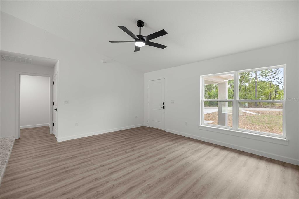 An empty room with light wood-look flooring, a ceiling fan, and a large window — 24013 NW TAMARIND LANE, DUNNELLON, FL