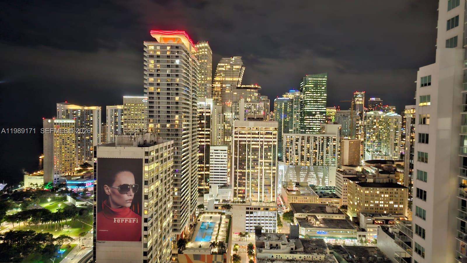 An elevated night view of the Miami skyline featuring illuminated skyscrapers and a large advertisement — 244 Biscayne Blvd # 3707, Miami FL 33132, MIAMI, FL