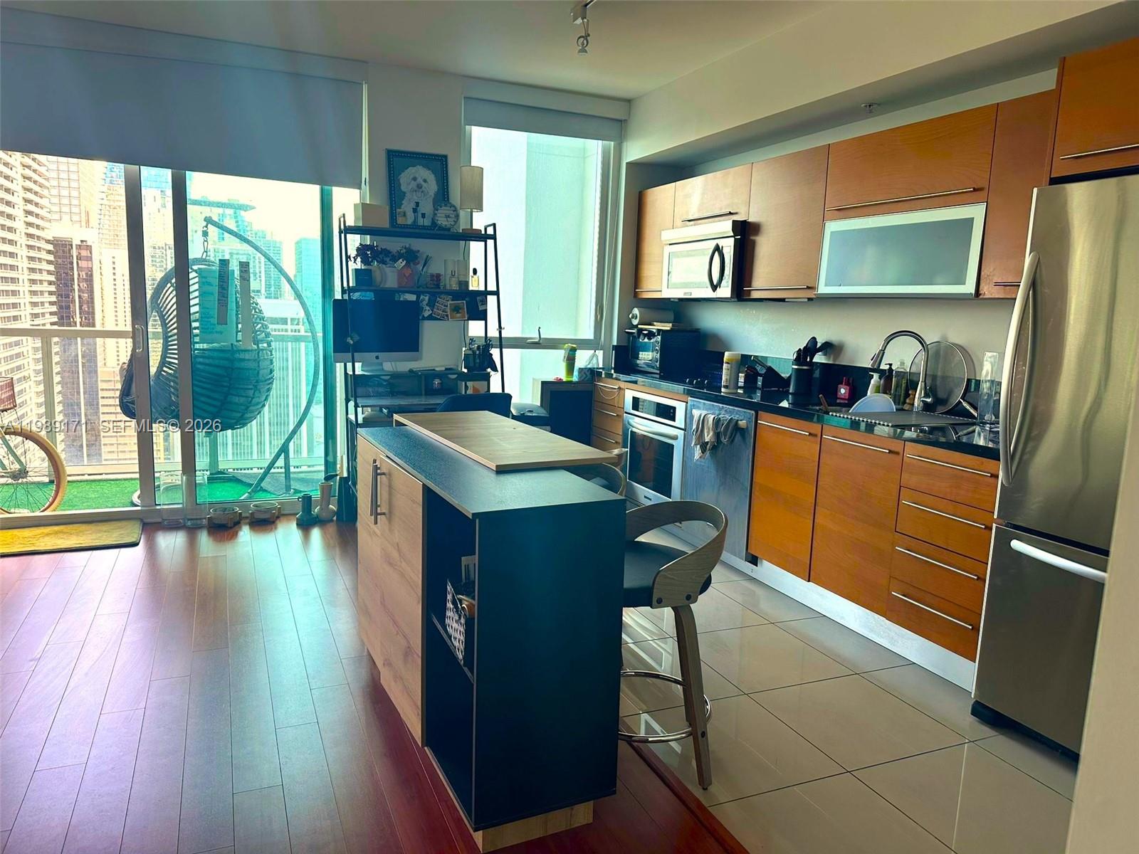 A modern kitchen features wood-toned cabinetry, stainless steel appliances, and a central island with seating — 244 Biscayne Blvd # 3707, Miami FL 33132, MIAMI, FL