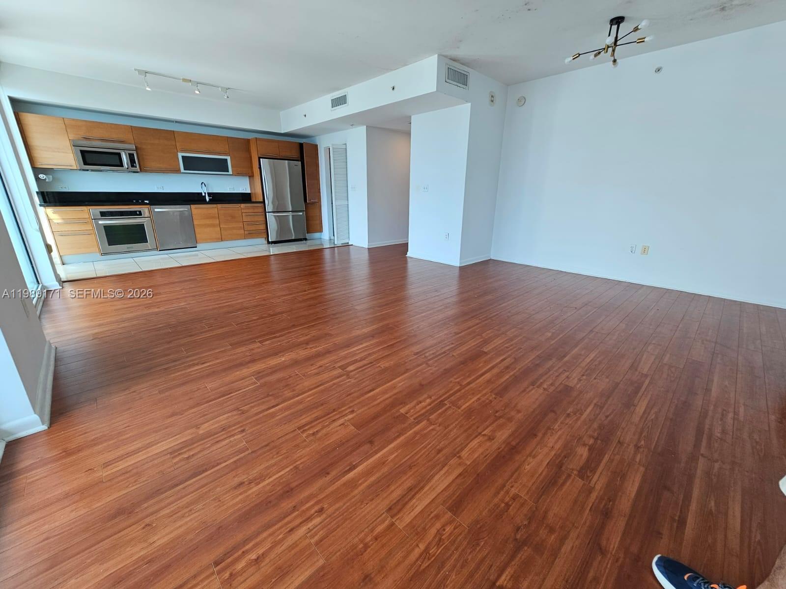 An open-concept living area features wood flooring, a modern kitchen, and a white ceiling — 244 Biscayne Blvd # 3707, Miami FL 33132, MIAMI, FL