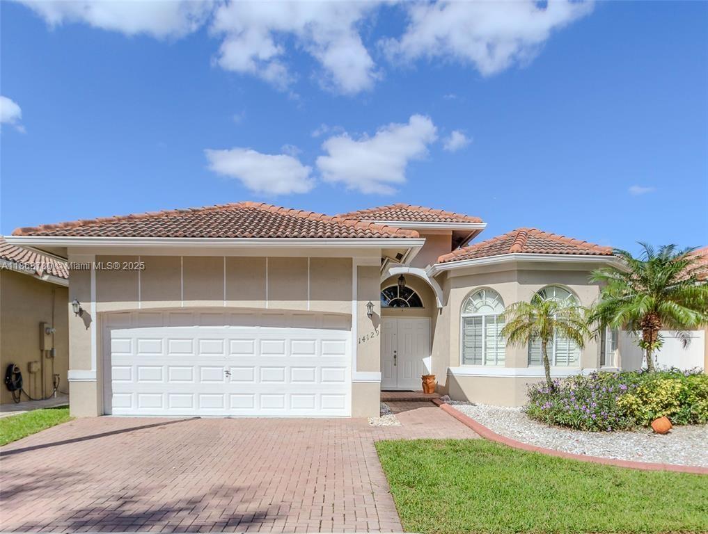 A single-story house with a tiled roof, a two-car garage, and a brick paver driveway — 14129 SW 31st St, Miramar FL 33027, MIRAMAR, FL