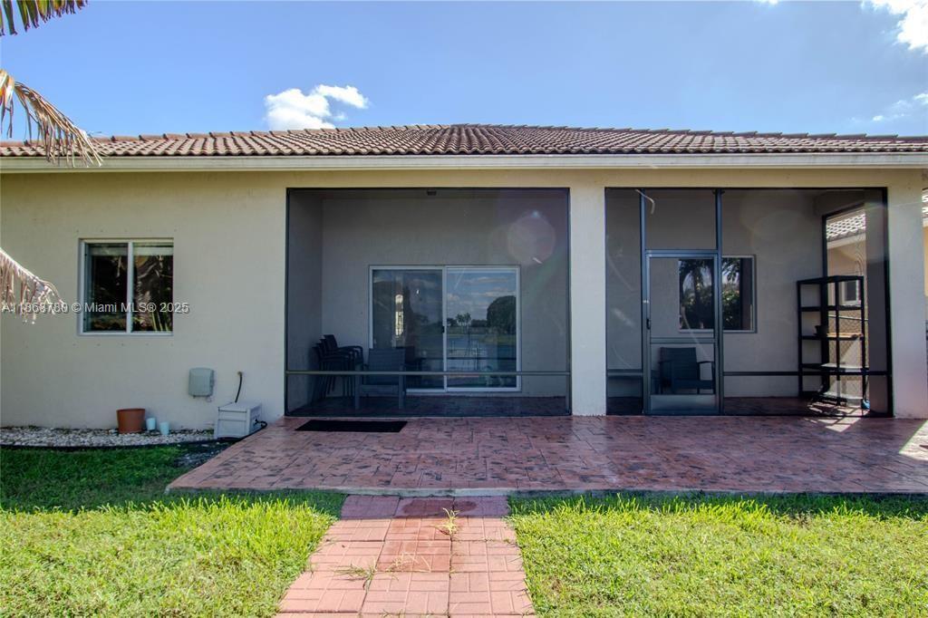 A screened-in patio with a stamped concrete floor overlooks a lake behind a house — 14129 SW 31st St, Miramar FL 33027, MIRAMAR, FL