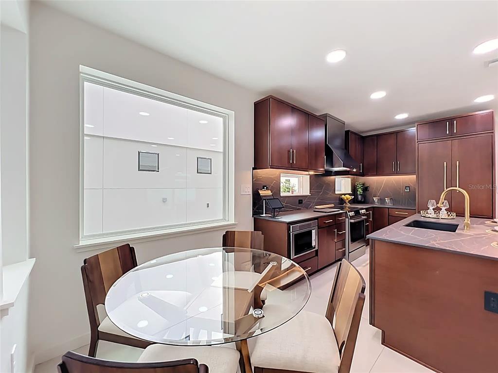A built-in refrigerator with wood paneling and gold hardware is set within a kitchen cabinet — 102 W PRINCETON STREET, ORLANDO, FL