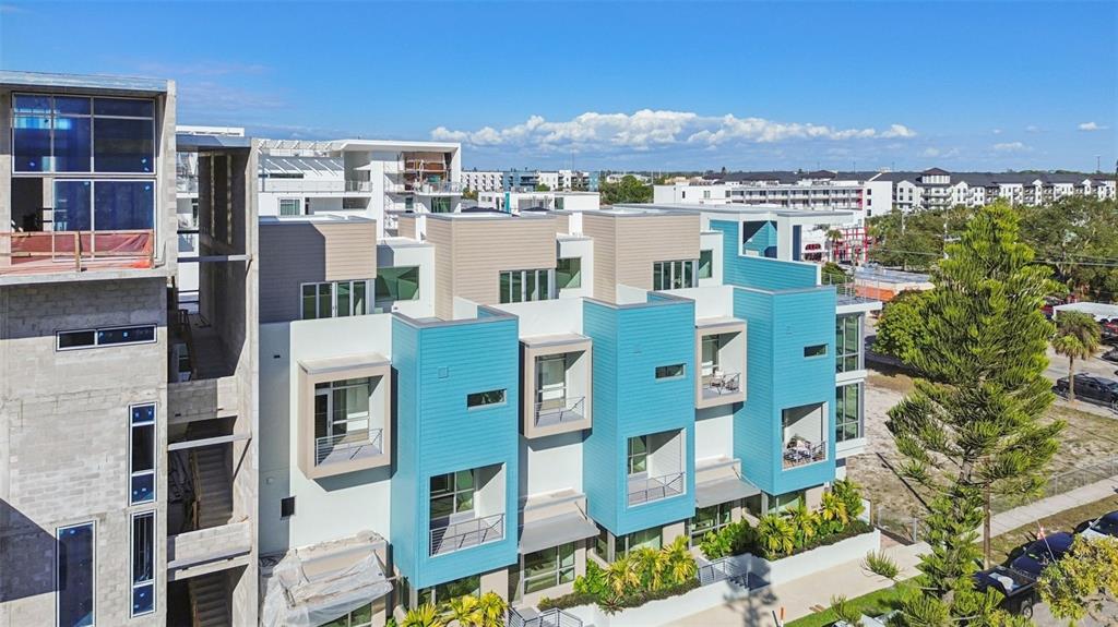 An aerial view shows a modern multi-story townhouse complex with blue and tan exterior siding — 1343 4TH STREET UNIT 102, SARASOTA, FL
