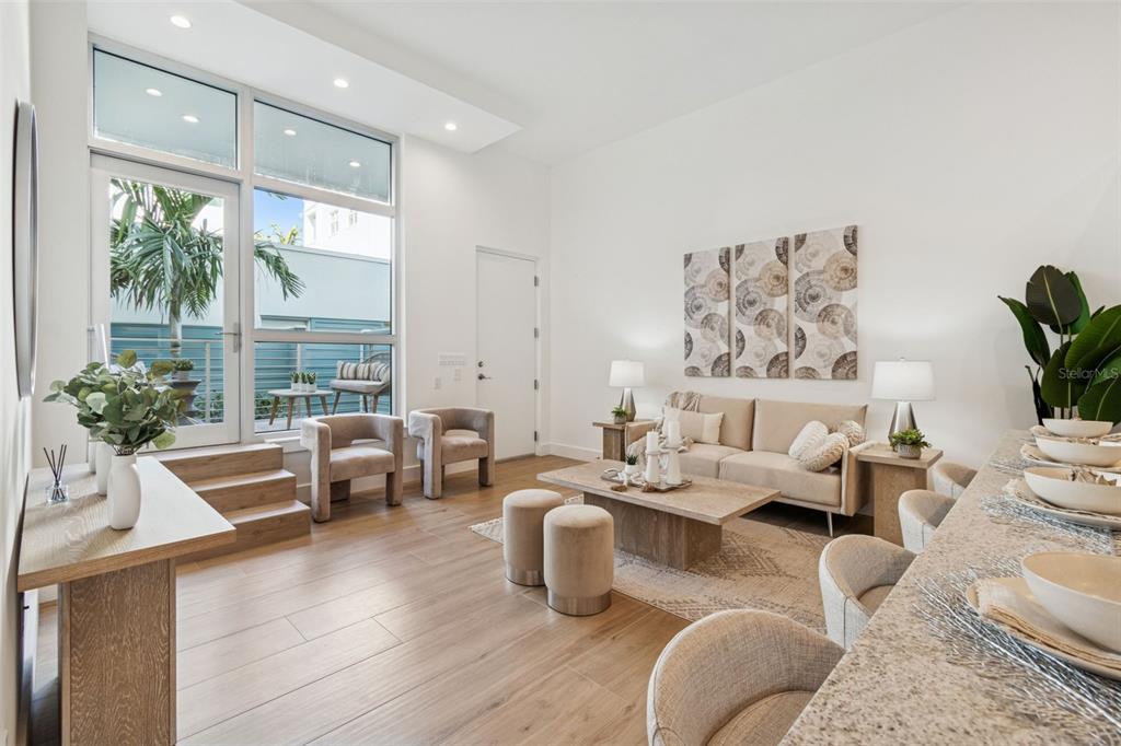 A modern living room features light wood flooring, a neutral sofa, and large glass doors — 1343 4TH STREET UNIT 102, SARASOTA, FL