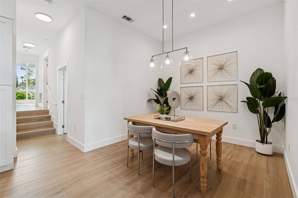 A dining area with a wooden table, four chairs, and wall art on light wood floors — 1343 4TH STREET UNIT 102, SARASOTA, FL