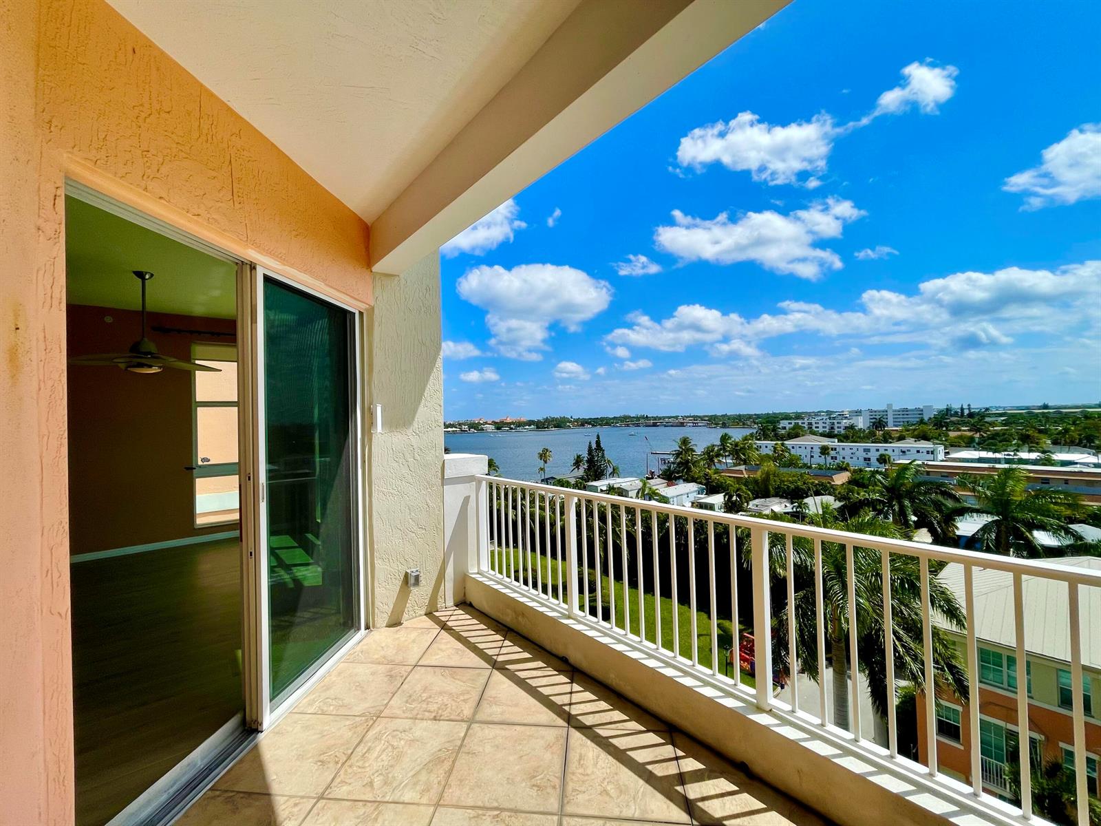 A tiled balcony with a white railing overlooks a body of water and palm trees — 804 E Windward Way, Lantana FL 33462, LANTANA, FL