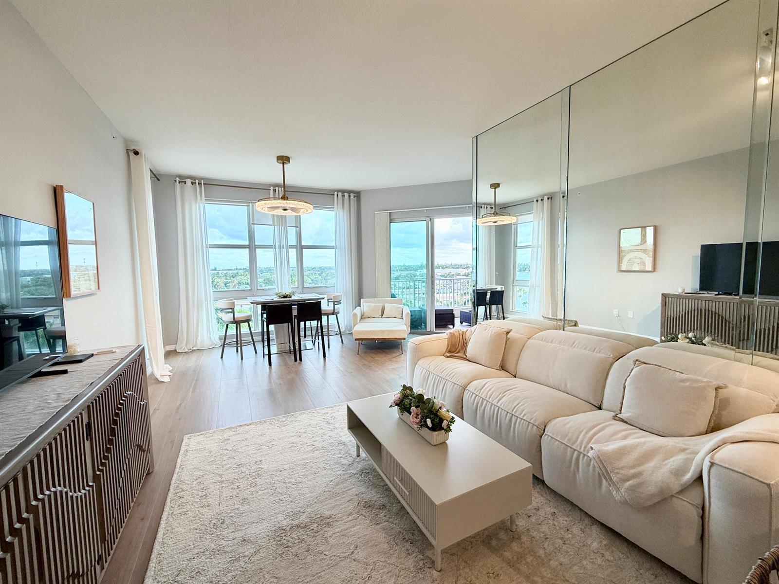 A bright living room features a white sofa, a coffee table, and floor-to-ceiling mirrors — 804 E Windward Way, Lantana FL 33462, LANTANA, FL