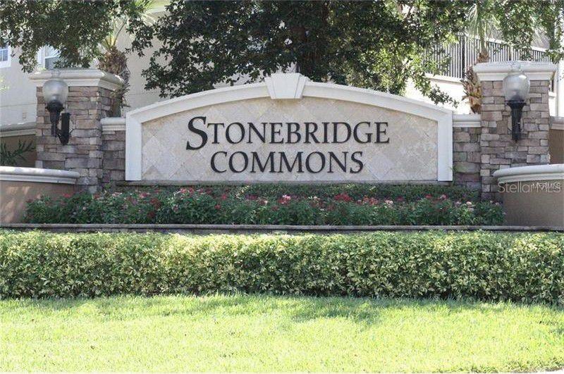 A stone monument sign for Stonebridge Commons stands in front of a landscaped garden area — 6453 ALCALDE CT UNIT 104, ORLANDO, FL