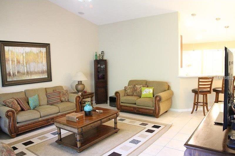 A living room features two tan sofas, a wooden coffee table, and a breakfast bar area — 6453 ALCALDE CT UNIT 104, ORLANDO, FL