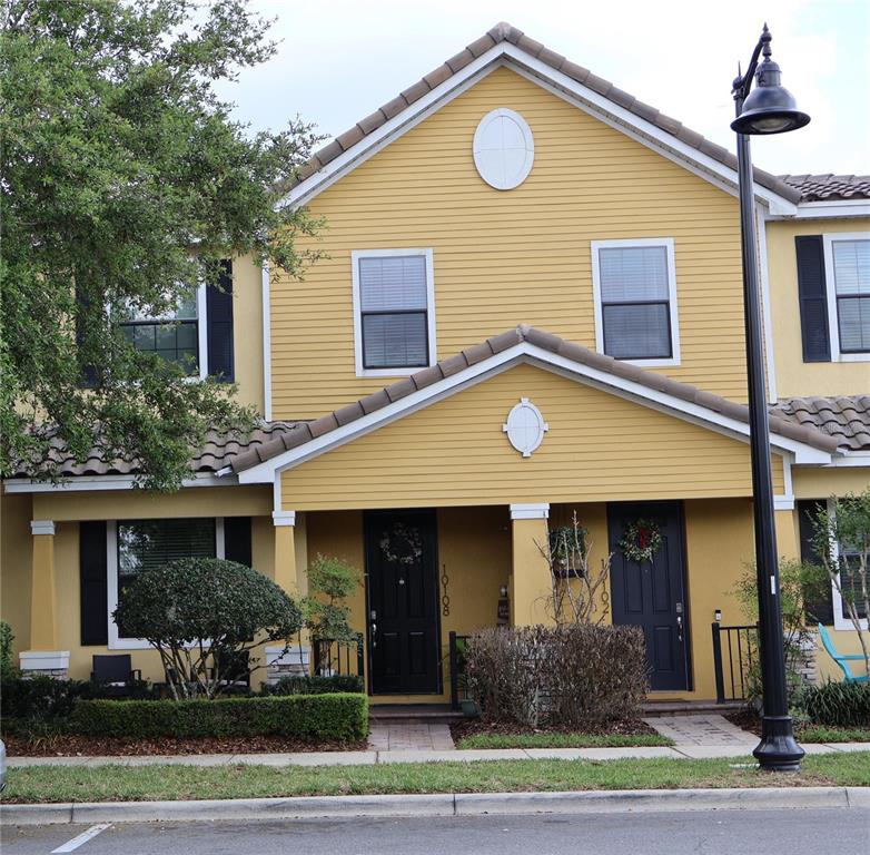 A yellow two-story townhouse with black doors and a dark shingled roof — 10108 EAGLE CREEK CENTER BOULEVARD, ORLANDO, FL