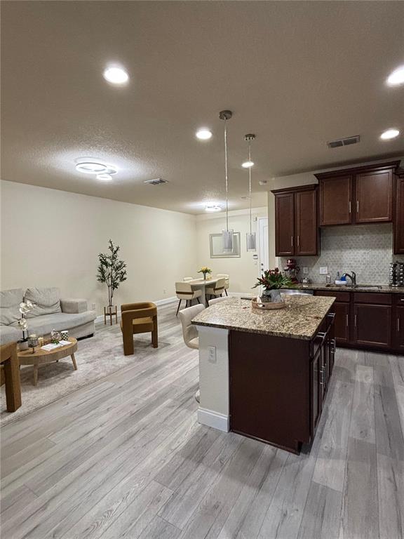 An open-concept kitchen with a granite island and dark wood cabinets overlooks a living area — 10108 EAGLE CREEK CENTER BOULEVARD, ORLANDO, FL