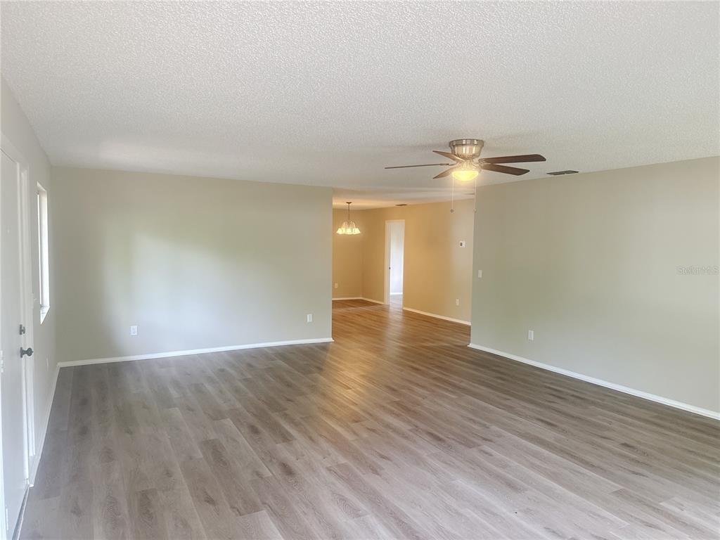 An open-concept living area features light-colored walls and wood-look laminate flooring — 11345 SE 188TH AVENUE, OCKLAWAHA, FL