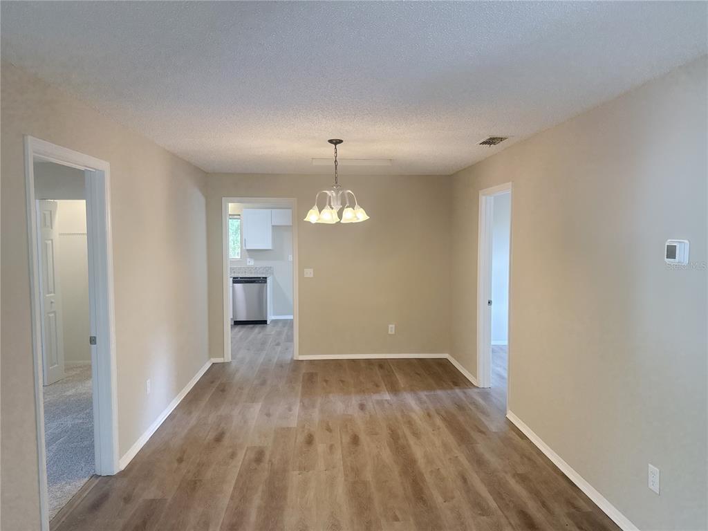 A dining area with light-colored walls, wood-look flooring, and a central chandelier — 11345 SE 188TH AVENUE, OCKLAWAHA, FL