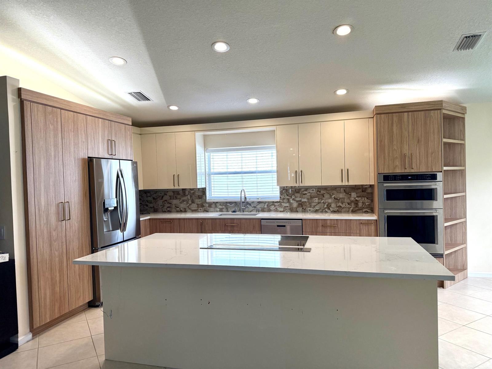 A modern kitchen features two-tone wood and cream cabinets, a large island, and stainless appliances — 8135 Playa Del Sur Boulevard, Lake Worth FL 33467, LAKE WORTH, FL