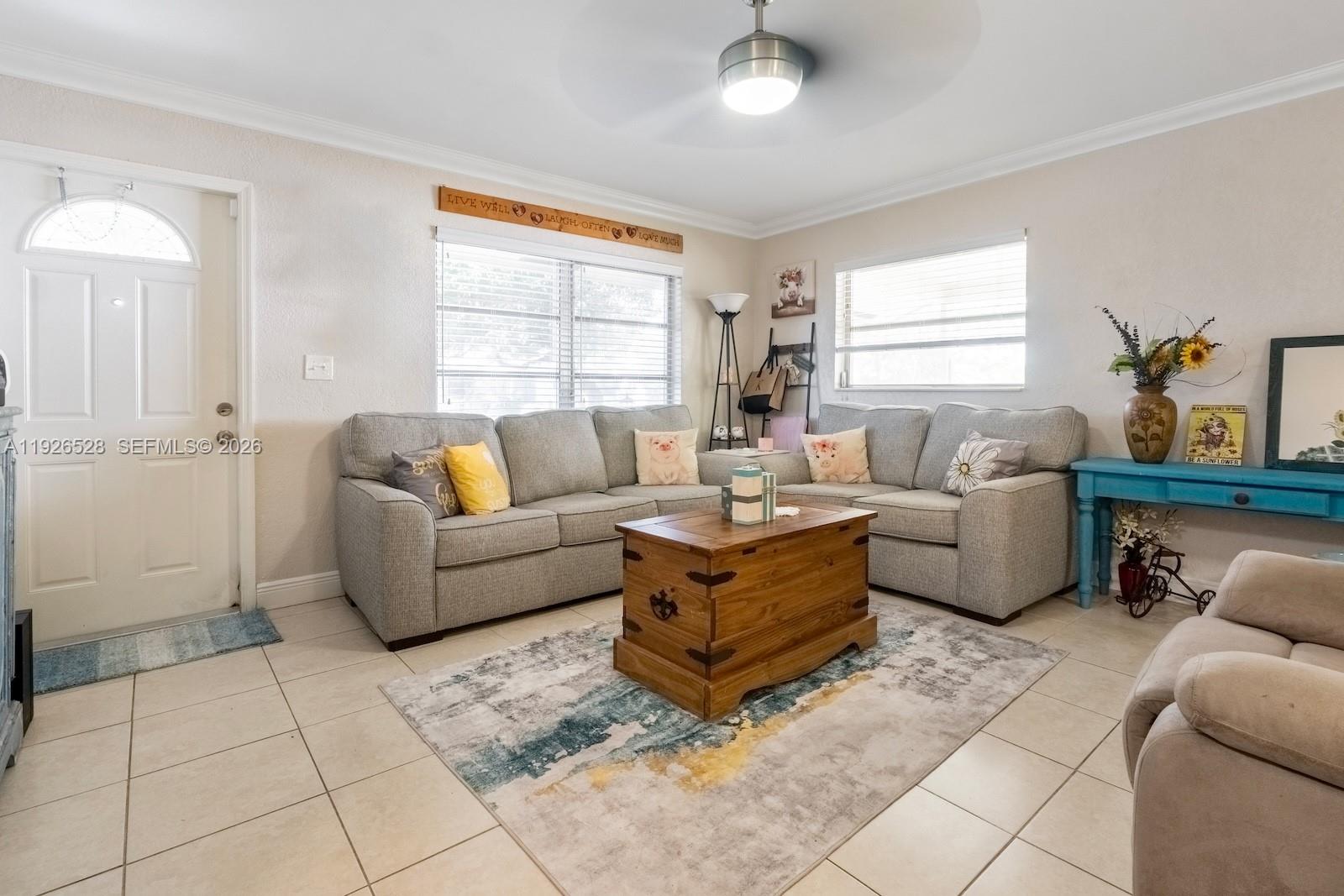 A living room features a grey sectional sofa, a wooden trunk coffee table, and tile flooring — 7002 NW 95th Ave, Tamarac FL 33321, TAMARAC, FL