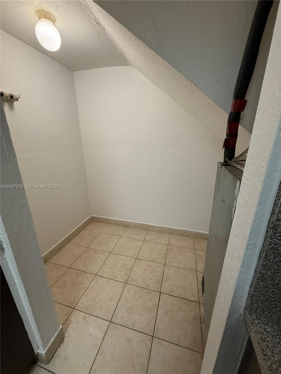 A small utility closet features beige tile flooring, white walls, and an exposed HVAC unit — 1305 W 53rd St # 406, Hialeah FL 33012, HIALEAH, FL