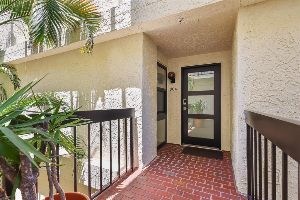 A brick walkway leads to the front door of a residential unit numbered 304 — 1935 GULF OF MEXICO DRIVE UNIT G7-304, LONGBOAT KEY, FL