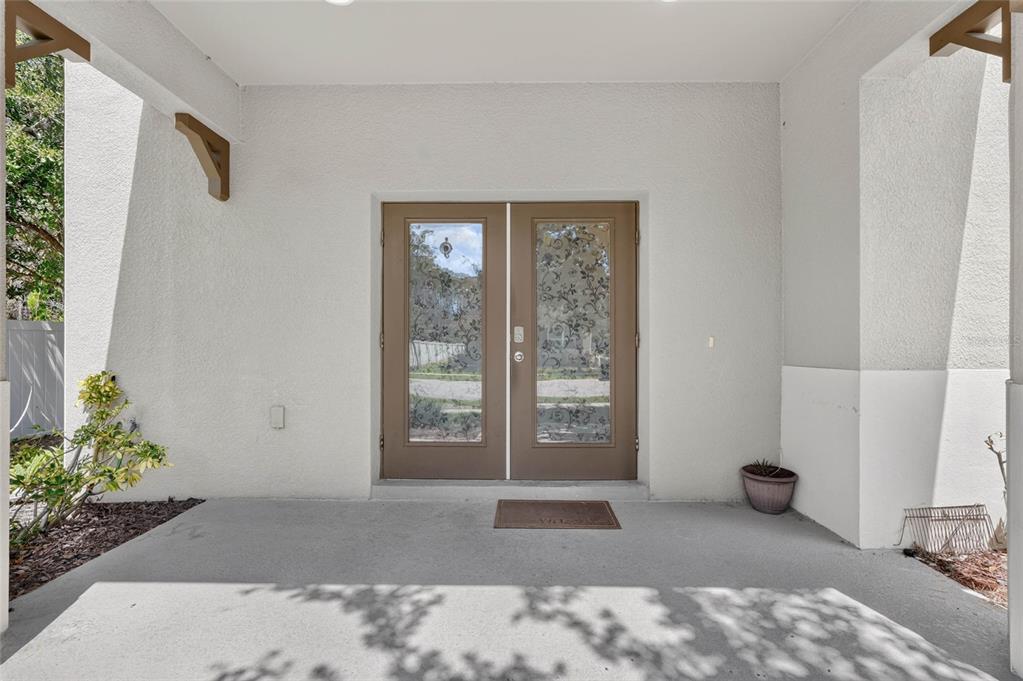 A covered concrete porch leads to a set of brown double doors with decorative glass — 1655 PHAM DRIVE, PORT ORANGE, FL