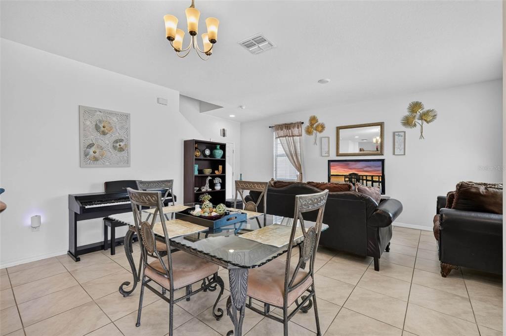 A dining area with a glass table and chairs sits in front of a living room — 1655 PHAM DRIVE, PORT ORANGE, FL