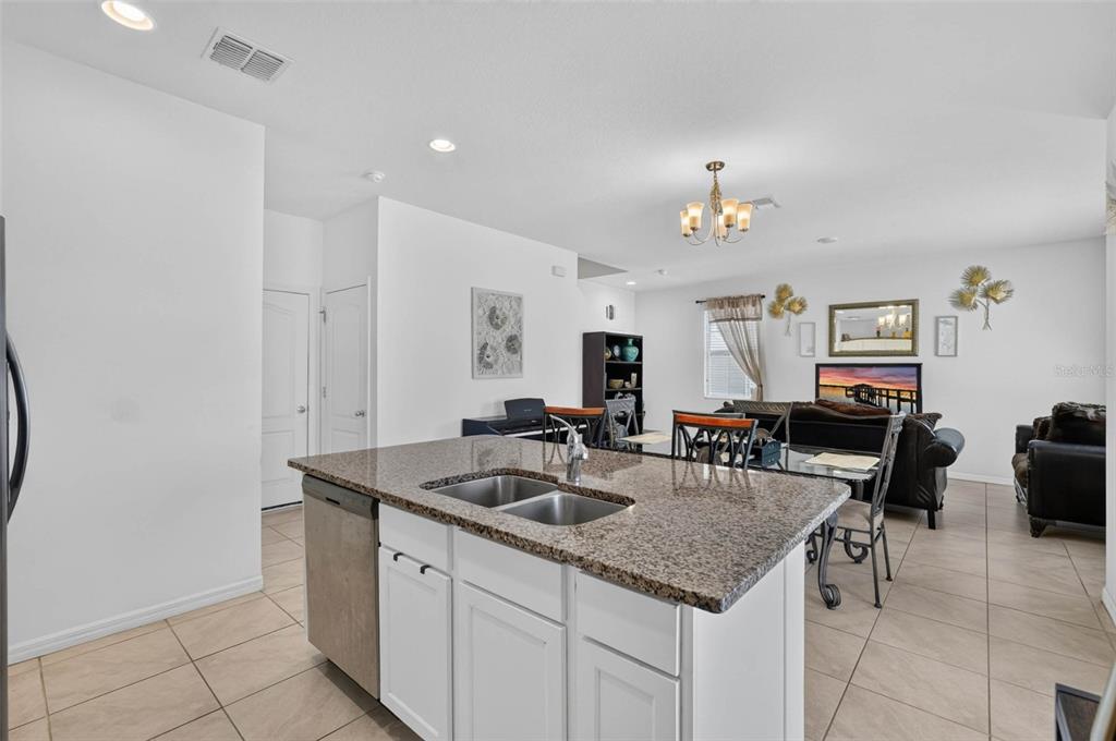 A kitchen island with a granite countertop and double sink overlooks an open living area — 1655 PHAM DRIVE, PORT ORANGE, FL