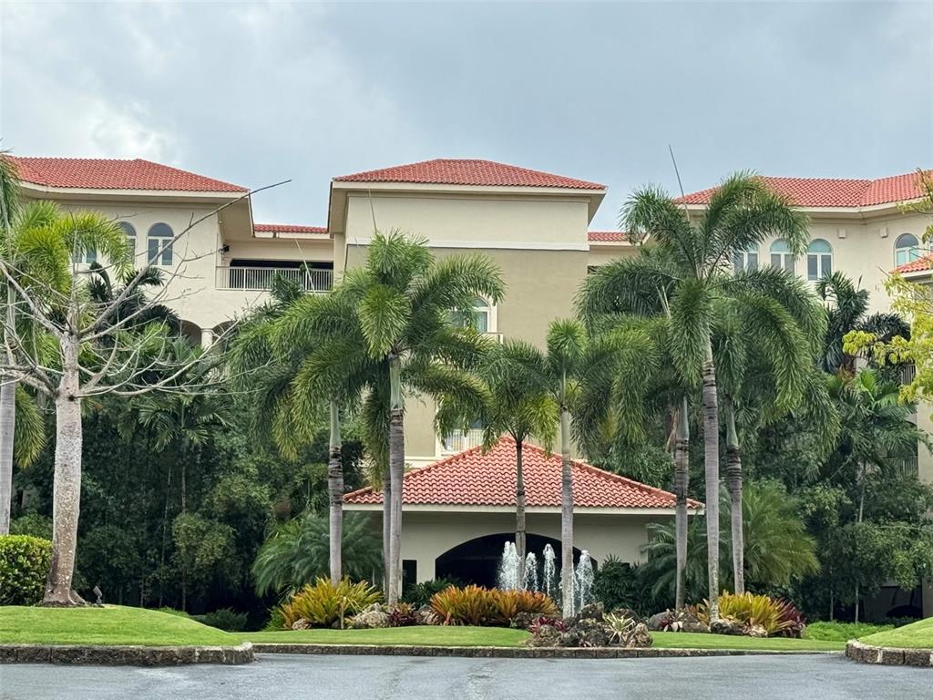 A multi-story building with a red tile roof, palm trees, and a front fountain — 500 PLANTATION DRIVE UNIT PH-3403, DORADO, PR