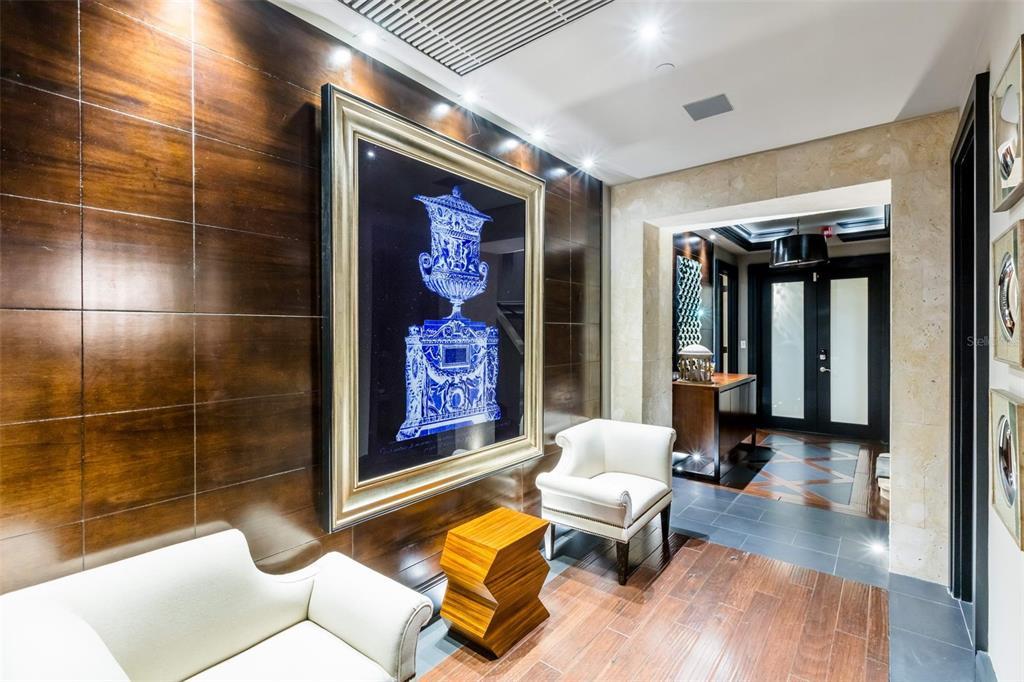 A modern entryway features wood-paneled walls, a large framed art piece, and two white chairs — 500 PLANTATION DRIVE UNIT PH-3403, DORADO, PR