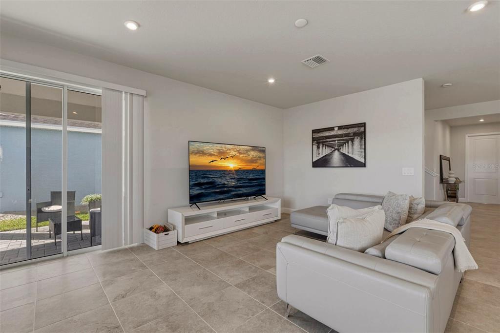 A living room features light tile floors, a white media console, and a gray sectional — 16390 QUEEN PALM DRIVE, PORT CHARLOTTE, FL