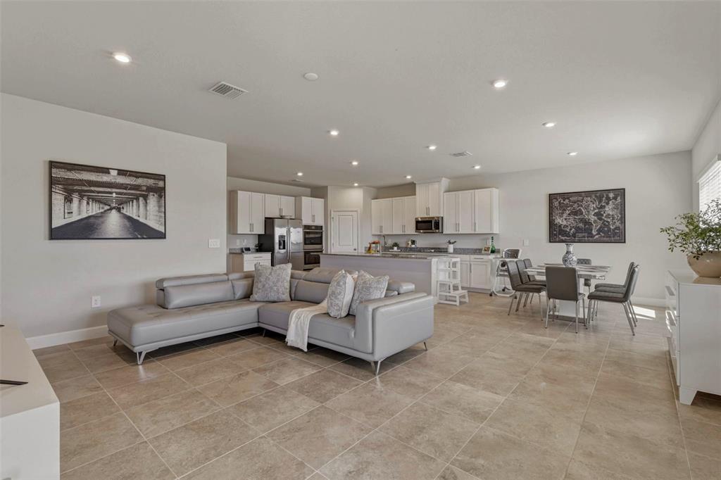 An open-concept living room and kitchen feature light gray tile flooring and white cabinetry — 16390 QUEEN PALM DRIVE, PORT CHARLOTTE, FL