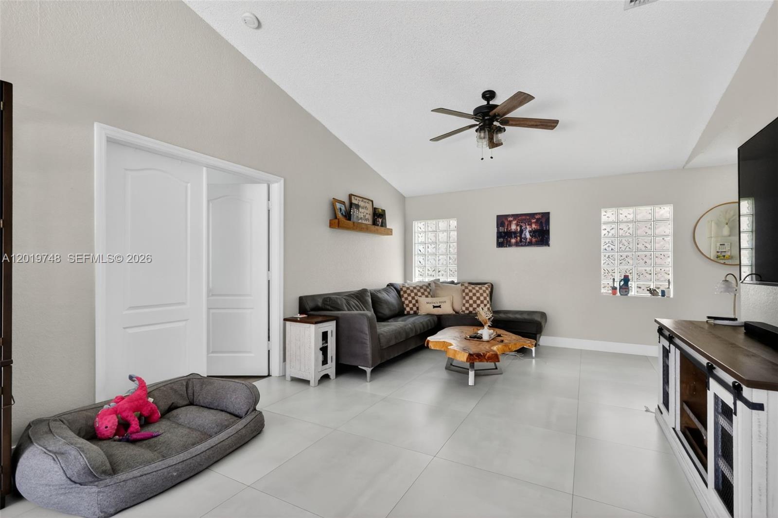 A living room features a grey sectional sofa, a live-edge coffee table, and glass blocks — 8061 NW 197th St, Hialeah FL 33015, HIALEAH, FL