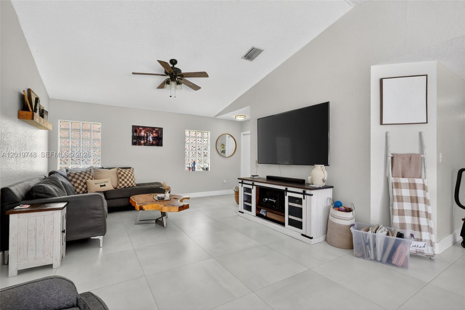 A living room features a gray sectional sofa, a live-edge coffee table, and a television console — 8061 NW 197th St, Hialeah FL 33015, HIALEAH, FL