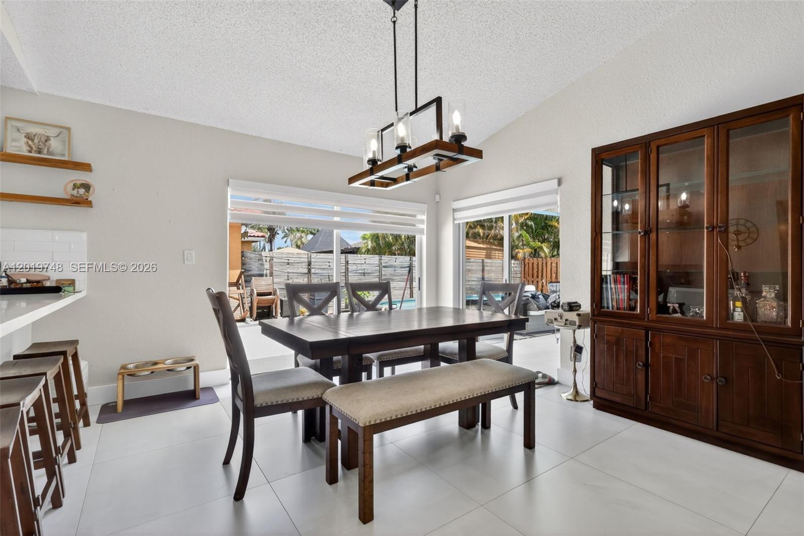 A dining room features a wooden table with chairs and a bench under a chandelier — 8061 NW 197th St, Hialeah FL 33015, HIALEAH, FL