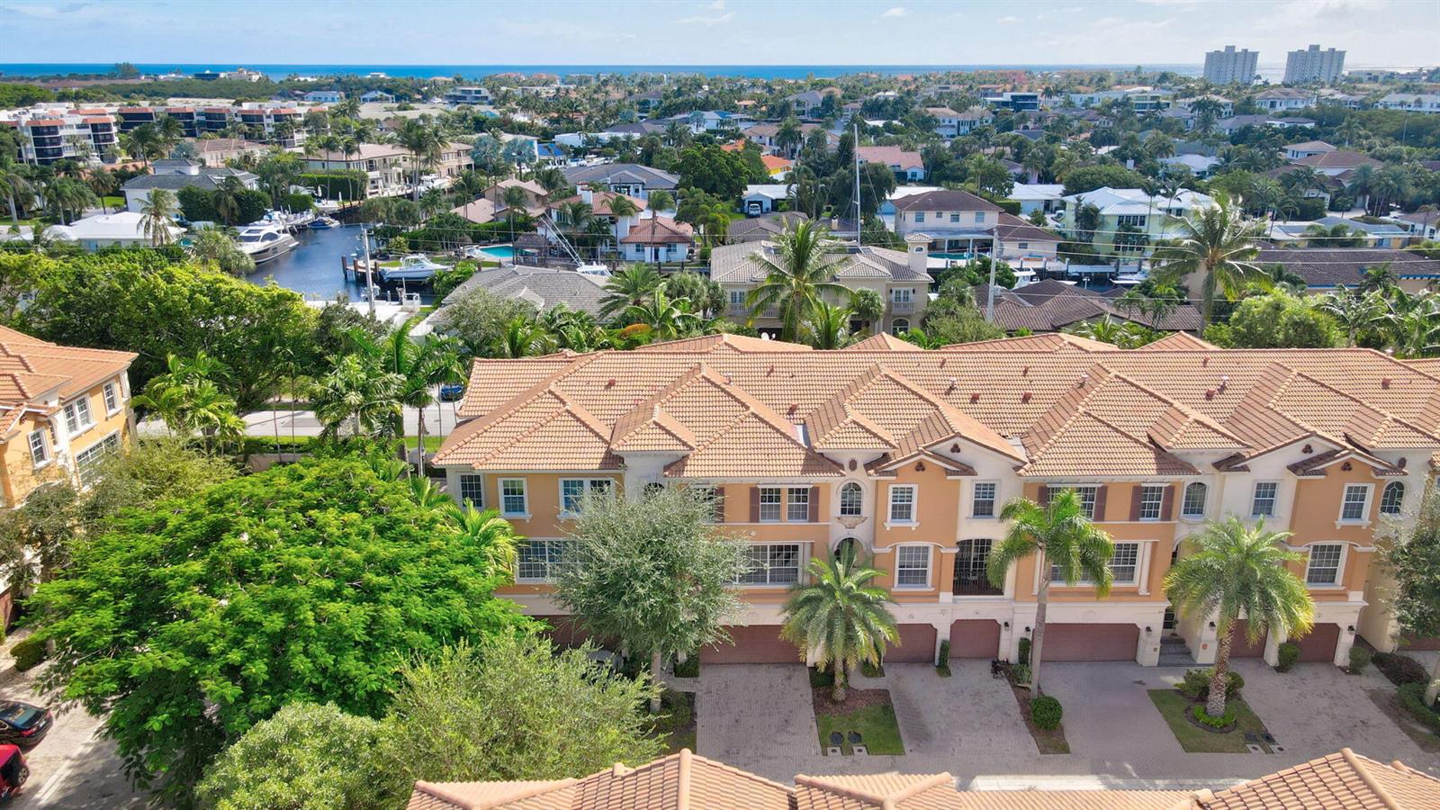 An aerial view shows a multi-story tan townhouse complex with a tiled roof and palm trees — 5660 NE Trieste Way, Boca Raton FL 33487, BOCA RATON, FL
