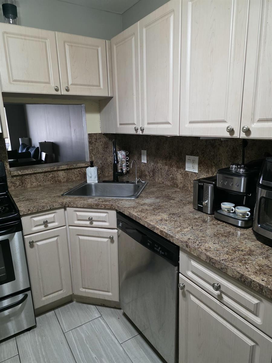 A kitchen features light wood cabinets, brown laminate countertops, stainless steel appliances, and tile flooring — 3130 Holiday Springs Boulevard # 307, Margate FL 33063, MARGATE, FL