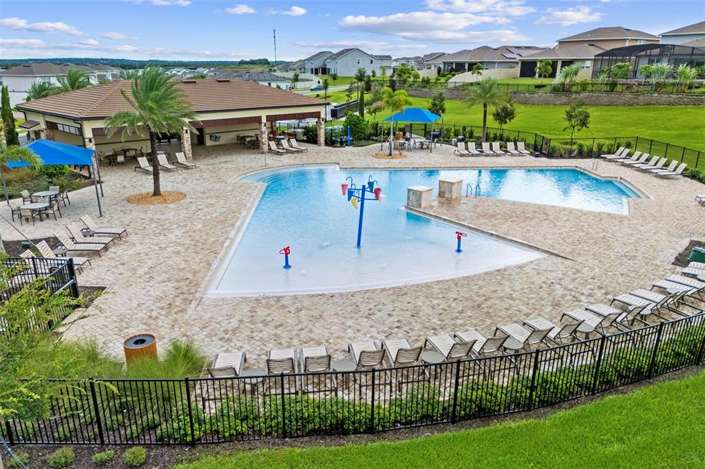 An outdoor community swimming pool with a splash pad, lounge chairs, and a covered pavilion — 7500 CATANIA LOOP, CLERMONT, FL