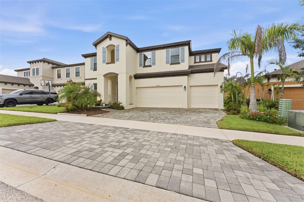 A two-story suburban house with a paved driveway, three-car garage, and light-colored stucco exterior — 13249 WILDFLOWER MEADOW DRIVE, RIVERVIEW, FL