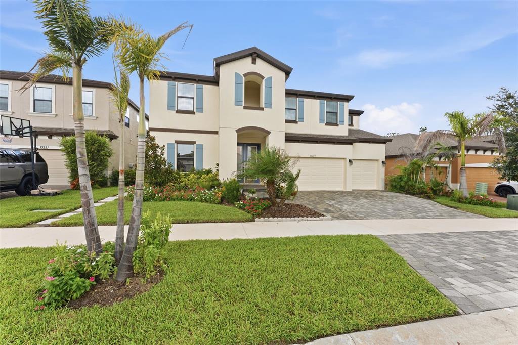 A two-story suburban house with a paved driveway, palm trees, and blue shutters — 13249 WILDFLOWER MEADOW DRIVE, RIVERVIEW, FL