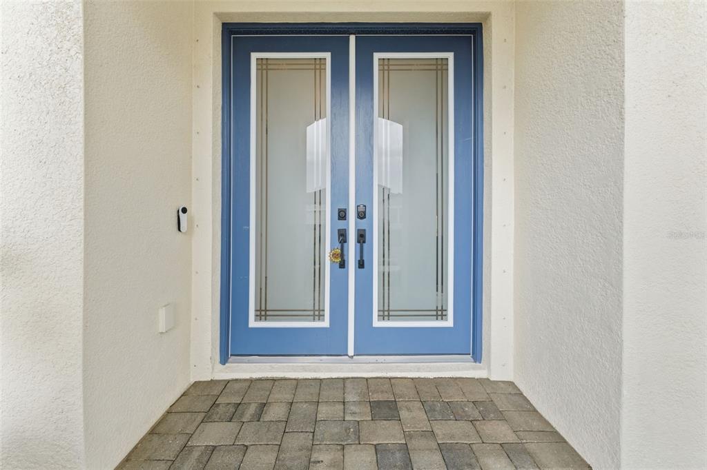 A set of blue double front doors with frosted glass panels and a paved entryway — 13249 WILDFLOWER MEADOW DRIVE, RIVERVIEW, FL