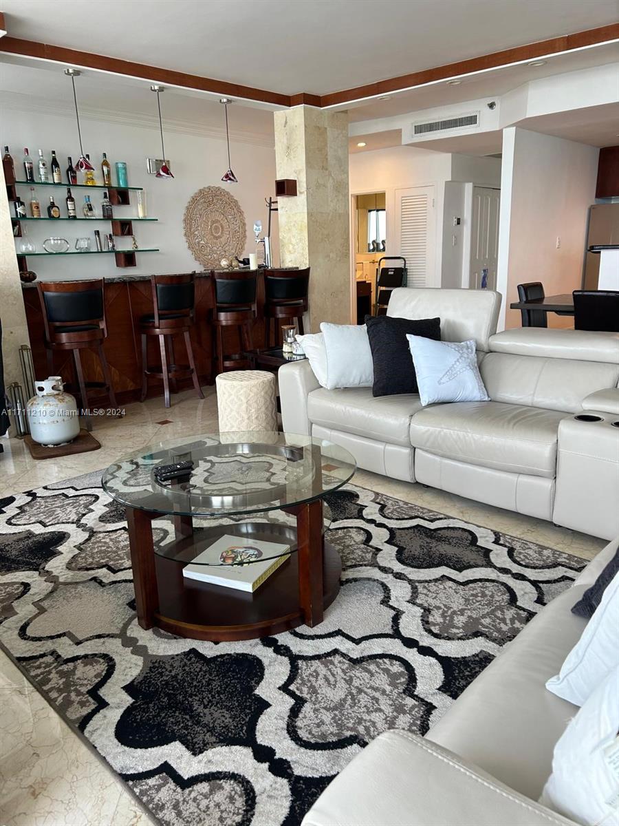 A living room features a bar area, a light-colored leather sofa, and a patterned rug — 100 Lincoln Rd, Miami Beach FL 33139, MIAMI BEACH, FL